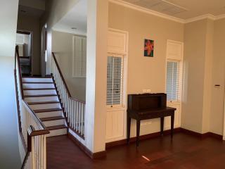 Spacious living area with staircase, wooden floors, and natural light