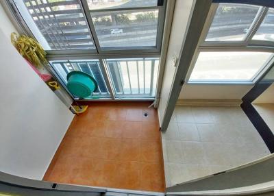 Compact balcony with terracotta tiled floor and safety railing overlooking the street