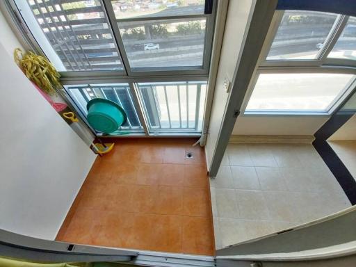 Compact balcony with terracotta tiled floor and safety railing overlooking the street