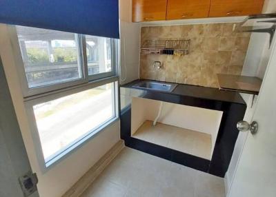 Compact kitchen with wooden cabinets and natural light