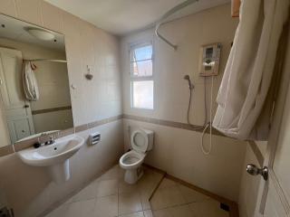 Compact bathroom with tiled walls, a sink, toilet, and shower area