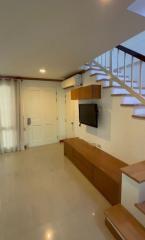 Modern living area interior with stairway and entertainment unit