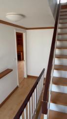 Wooden stairway with white walls leading to a room