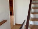 Wooden stairway with white walls leading to a room