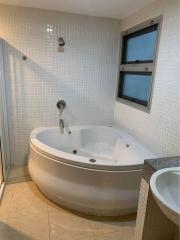 Corner Jacuzzi-style tub in a tiled bathroom with a window