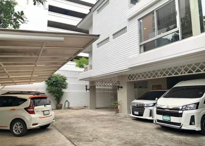 White modern two-storey house with carport and parked cars