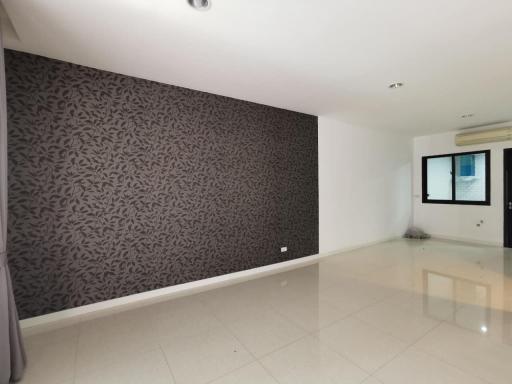 Spacious and bright living room with patterned accent wall and glossy floor