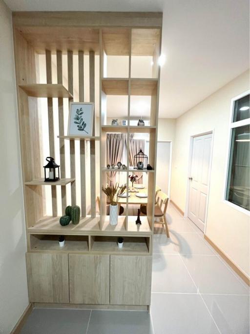 Modern living area with decorative shelving unit, leading to a dining space