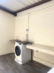Compact laundry area with modern washing machine and built-in counter