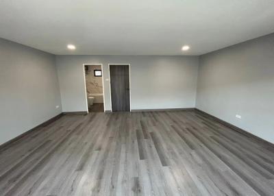 Spacious bedroom with modern laminate flooring and neutral color walls