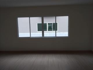 Spacious empty bedroom with large window providing natural light