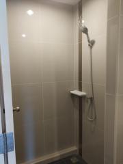 Modern bathroom with wall-mounted showerhead and neutral tiles