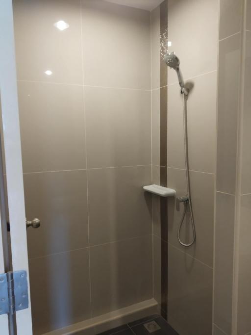 Modern bathroom with wall-mounted showerhead and neutral tiles