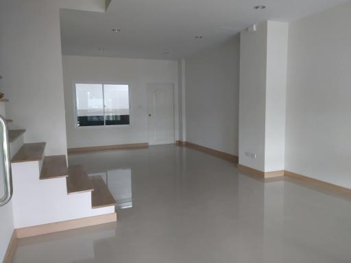 Spacious and well-lit empty living room interior with glossy floor and staircase