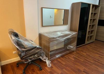 Partial view of a bedroom with new furniture still wrapped in plastic