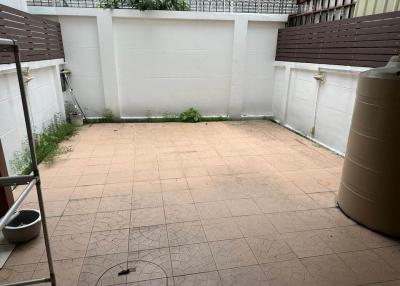 Paved backyard with privacy fence and storage tank