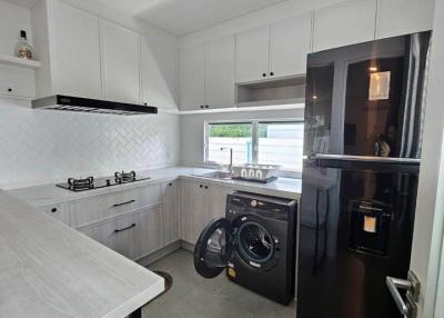 Modern Kitchen with Marble Countertops, Stainless Steel Appliances, and Integrated Laundry