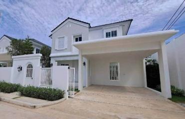 White two-story house with covered carport and fenced front yard