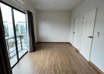 Spacious bedroom with wooden flooring, air conditioning, and balcony access