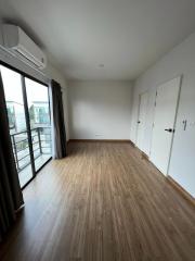 Spacious bedroom with wooden flooring, air conditioning, and balcony access