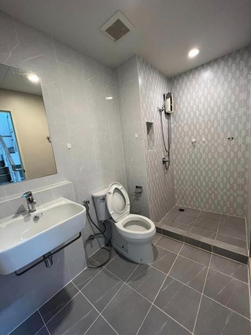 Modern bathroom with tiled floors and walls, and essential fixtures