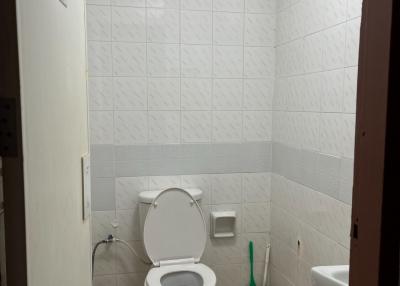 Compact white-tiled bathroom with toilet and bidet