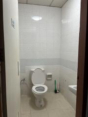 Compact white-tiled bathroom with toilet and bidet