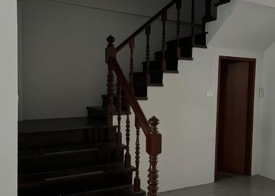Wooden staircase in a home with white walls and tiled floor