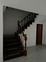 Wooden staircase in a home with white walls and tiled floor