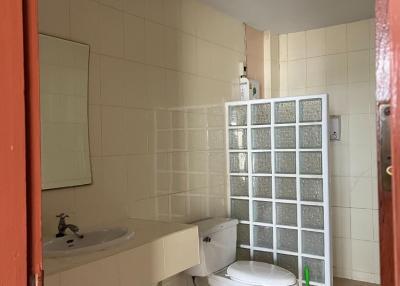 Compact bathroom with white fixtures, including a toilet and sink, and a glass partition