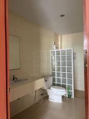 Compact bathroom with white fixtures, including a toilet and sink, and a glass partition