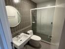 Modern bathroom with a glass shower enclosure and gray tiling