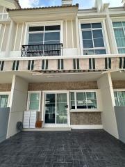 Exterior view of a modern residential townhouse with balcony and paved patio