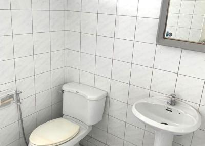Compact bathroom with white tiles and checkerboard floor