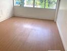 Empty bedroom interior with wooden flooring and large windows