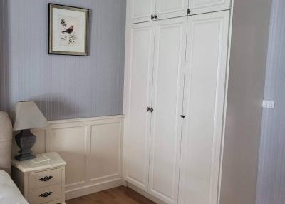 Cozy bedroom interior with wooden flooring and elegant white wardrobe