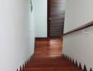 Wooden staircase leading to upper floor with white walls and modern design