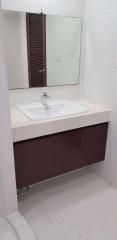 Modern bathroom with white tiles and wooden cabinet