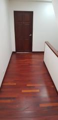 Warmly lit hallway with wooden flooring and a closed wooden door