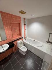 Modern bathroom with a combination of orange and white tiles, featuring a bathtub, toilet, and sink