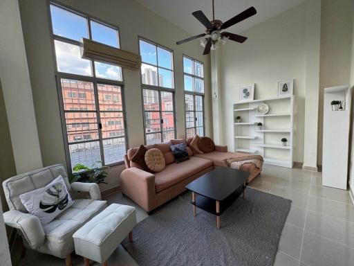 Spacious living room with high ceilings, large windows, and modern furnishings