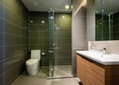 Modern bathroom with glass shower and dark wall tiles