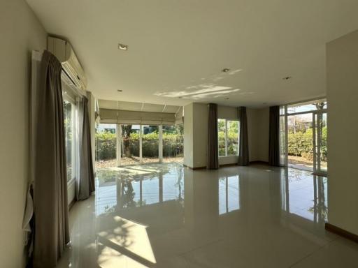 Spacious and well-lit living room with large windows and a glass door leading to an outdoor area