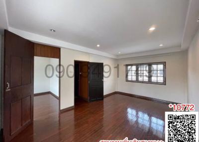 Spacious and well-lit bedroom with polished wooden flooring and large window