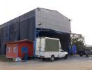 Exterior view of an industrial warehouse with a white truck parked outside