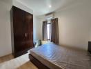 Spacious bedroom with large window and wooden wardrobe