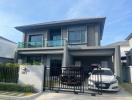 Modern two-story house with balcony and a parked car