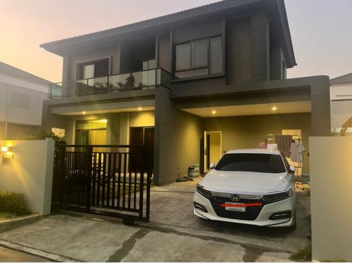 Modern two-story house with a car parked in the driveway during twilight