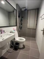 Modern bathroom with tiled floors and walls, equipped with a sink, toilet, and shower