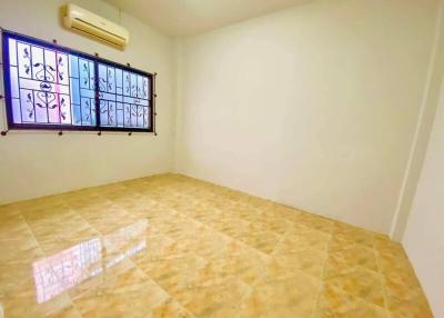 Empty bedroom with tiled flooring and window with security grill